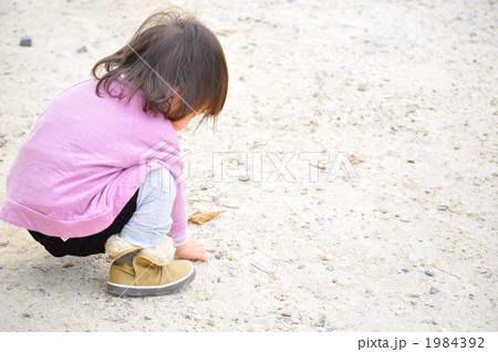 子供 女の子 しゃがむ 道の写真素材