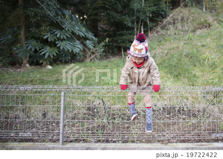 子供 女の子 フェンス 乗り越えるの写真素材