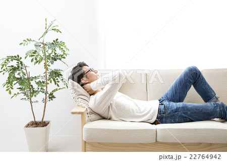 男性 ソファ 寝る 休むの写真素材