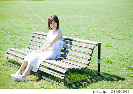 女性 夏 ベンチ 座るの写真素材