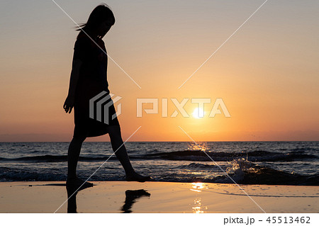女性 1人 海 影 太陽 人物 夕日 日没の写真素材