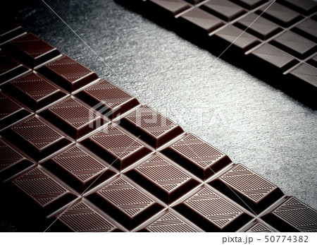 Black chocolate bar on black slate plate