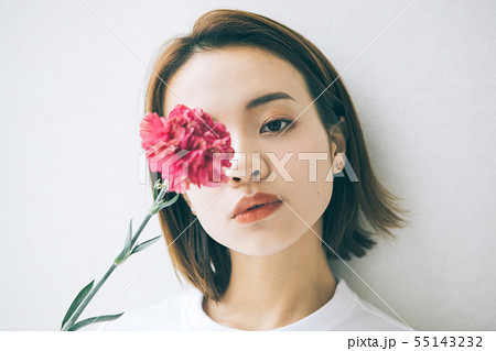 女性 花 白バック 一輪の写真素材