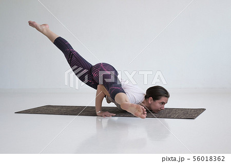 Young slim woman in the white hood sitting on the yoga mat with