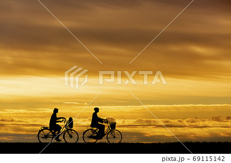 夕焼け 自転車 夕陽 土手 シルエット 影の写真素材