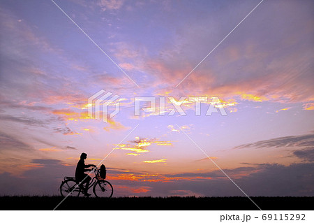 夕焼け 自転車 夕陽 土手 シルエット 影の写真素材
