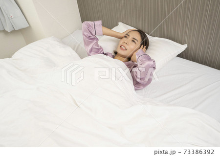 病気で寝込んでいる女性/体調の悪い女性/ベットに寝ている美しい女性