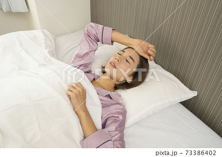 病気で寝込んでいる女性/体調の悪い女性/ベットに寝ている美しい女性