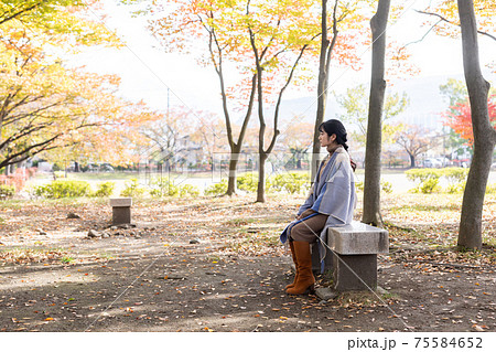 女性 公園 ベンチ 座るの写真素材