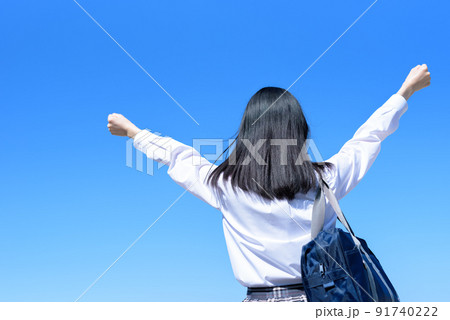 青空 女性 ガッツポーズ 後姿の写真素材